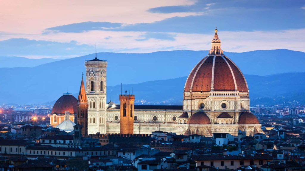 Silhouette of Florence, Italy against a vibrant sunset sky, featuring iconic landmarks and domes.