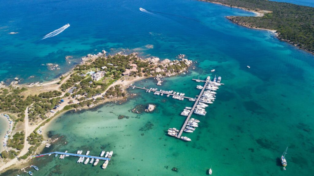 Aerial view of Costa Smeralda in Sardinia, Italy, showcasing pristine beaches, turquoise waters, and luxurious resorts surrounded by lush Mediterranean landscapes.