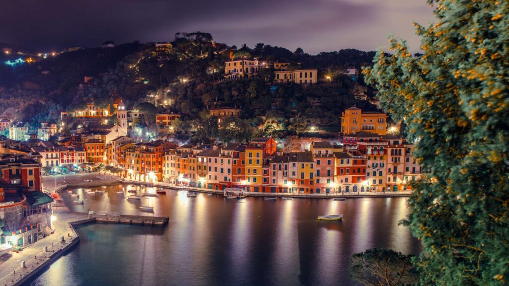 Panoramic view of the charming Portofino on the Italian Riviera, bathed in golden sunlight and surrounded by azure waters.