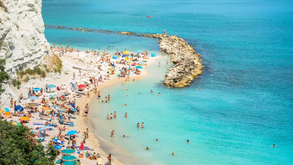 Sirolo Beach in Conero National Park, Italy, a pristine coastal paradise with turquoise waters, golden sands, and rugged cliffs.