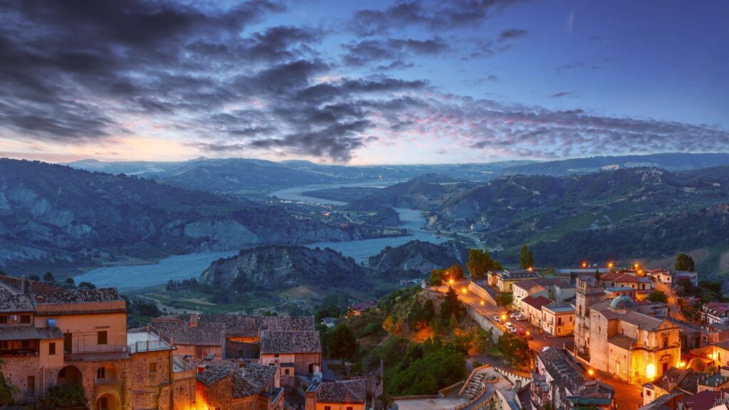 Evening view of Stilo Village in Calabria, Italy, featuring historic architecture and a tranquil ambiance under the setting sun.