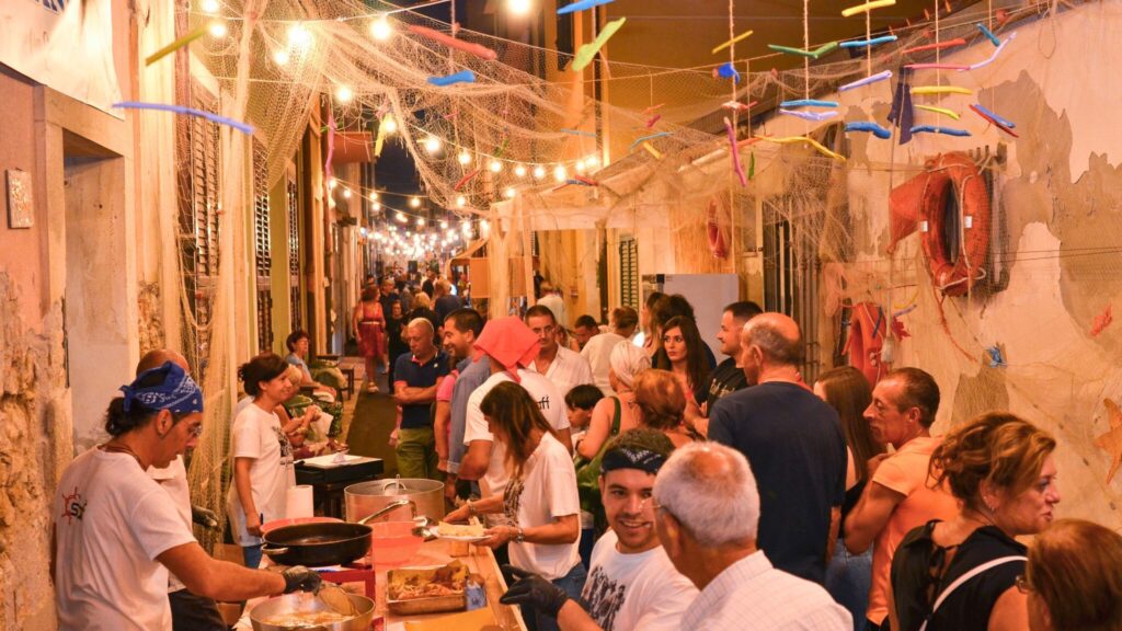A bustling scene at an Italian food festival, with colorful tents, tables laden with food, and people enjoying culinary delights amidst a backdrop of historic architecture.