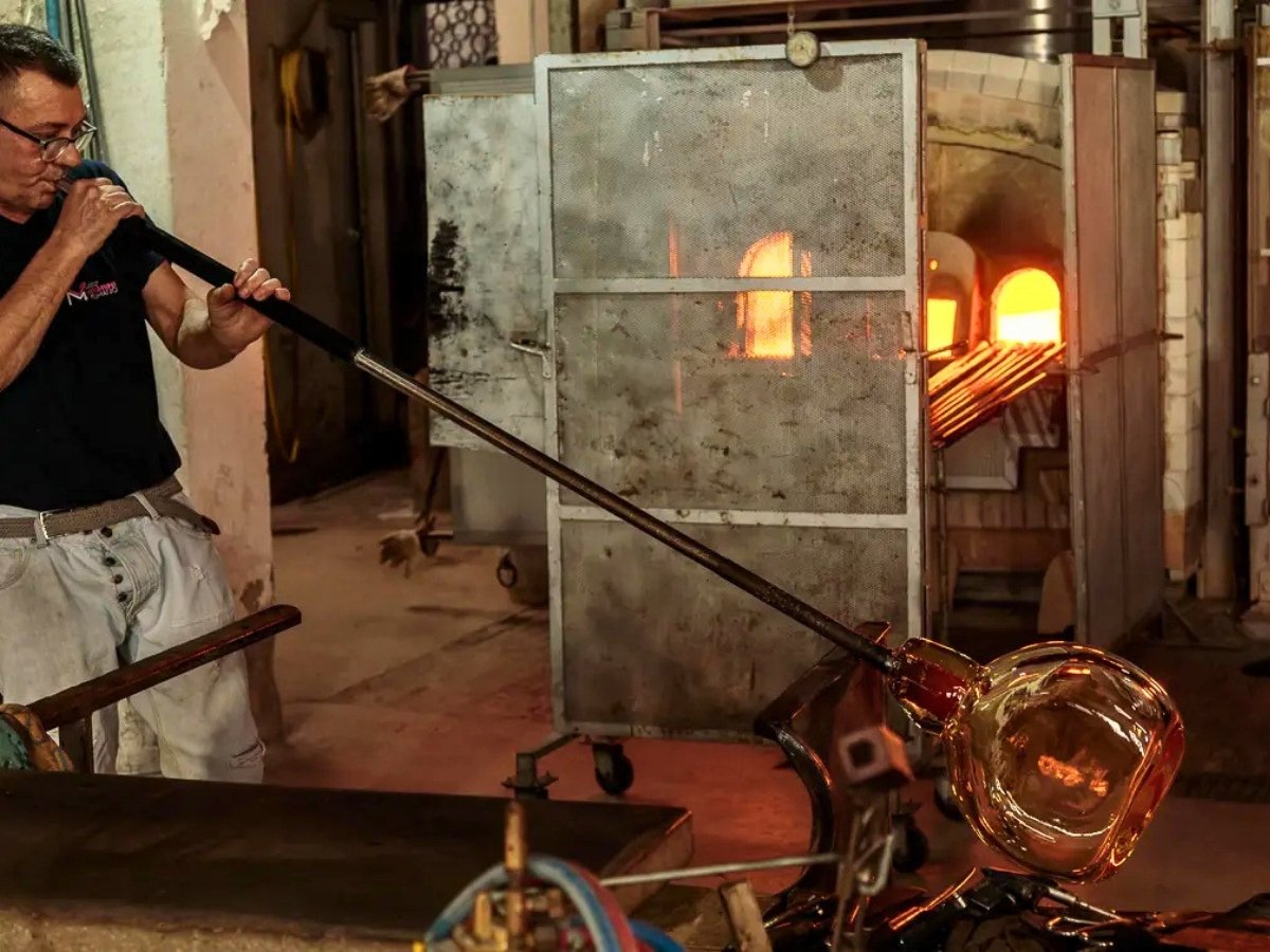 Master artisan glassblower in a Murano workshop shaping molten glass