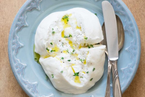 Delicious Burrata cheese from Puglia adorned with olive oil, thyme, salt, and pepper, showcasing its creamy texture and rich flavors.
