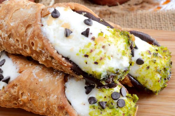 Close-up of delectable Cannoli Siciliani pastry, showcasing crispy shells, creamy ricotta filling, and a dusting of powdered sugar.