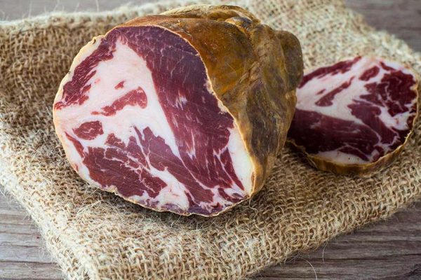 Close-up of Capocollo di Martina Franca, a traditional Italian cured meat, showcasing its marbled texture and savory aroma.