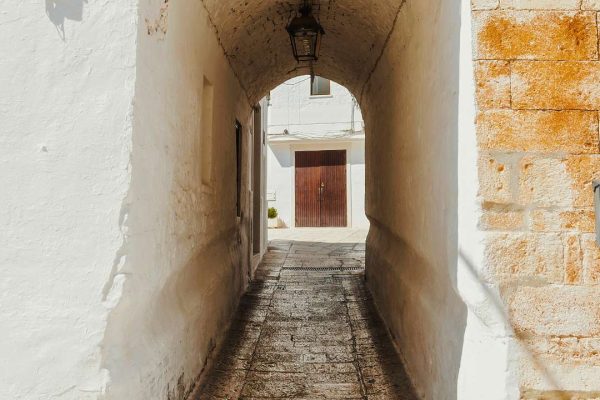 Quaint little alley in the medieval center of the white village of Cisternino, Italy, featuring charming architecture and cobblestone streets.