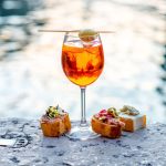 A refreshing Spritz Aperol with cicchetti, showcasing the vibrant colors of the cocktail and the delicious variety of Italian appetizers.