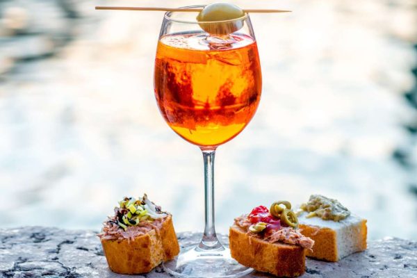A refreshing Spritz Aperol with cicchetti, showcasing the vibrant colors of the cocktail and the delicious variety of Italian appetizers.